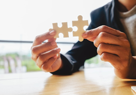 Photo of man holding two puzzle pieces.